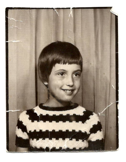 Marlies as a child, smiling, in a striped jumper